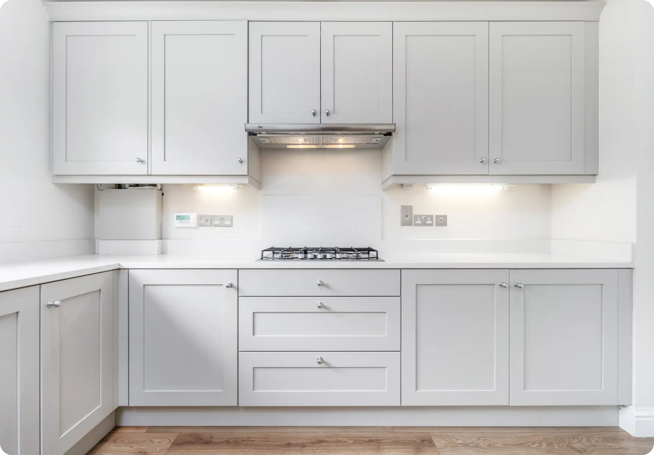 Modern white kitchen with built-in stove and ample cabinetry.